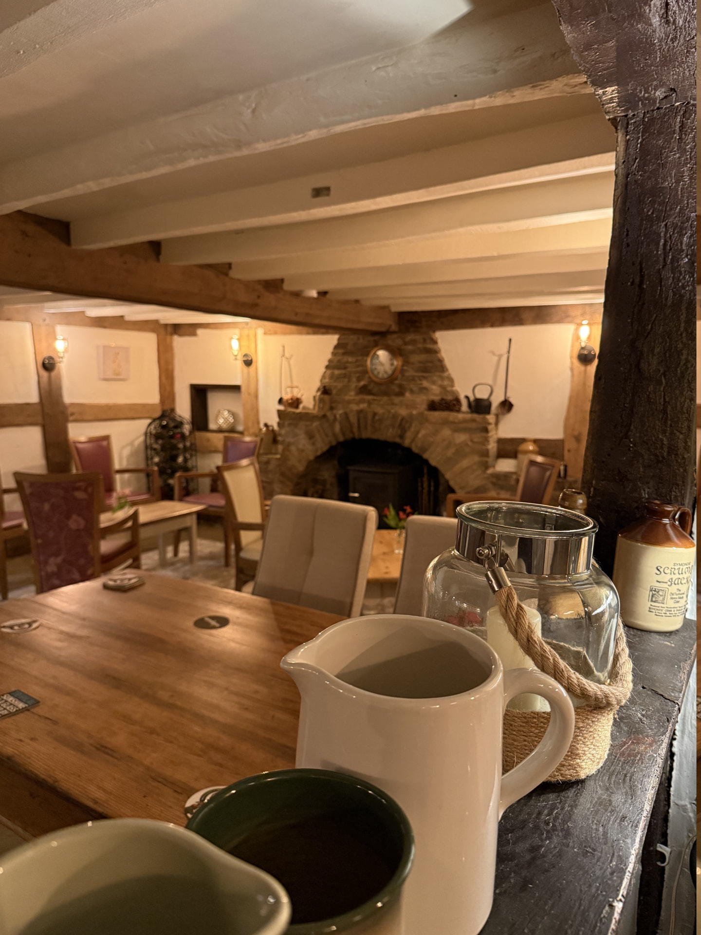 View across the snug towards the stone fireplace, with jugs on a worn timber bar