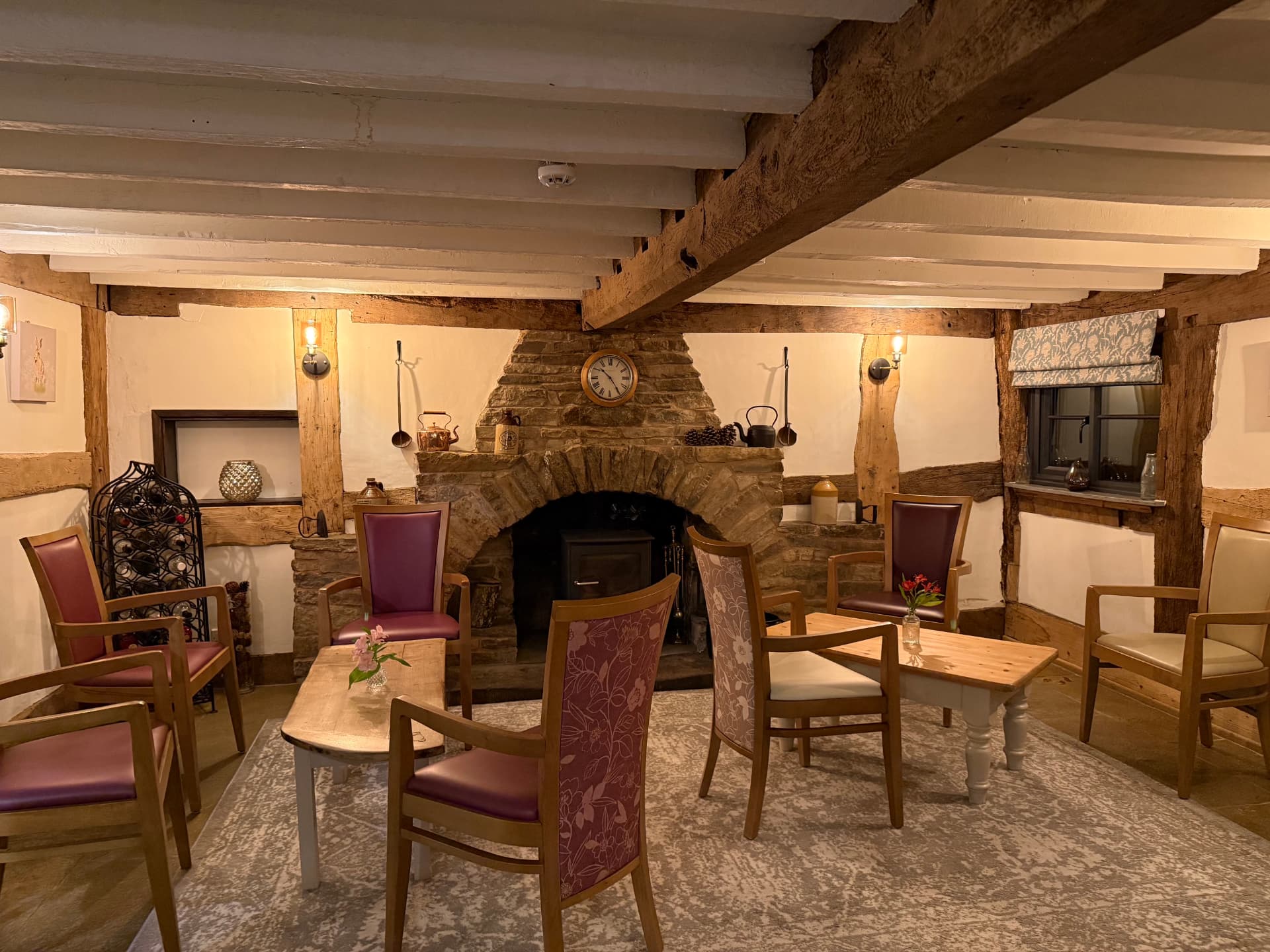 Armchairs and tables gathered around the stone inglenook fireplace