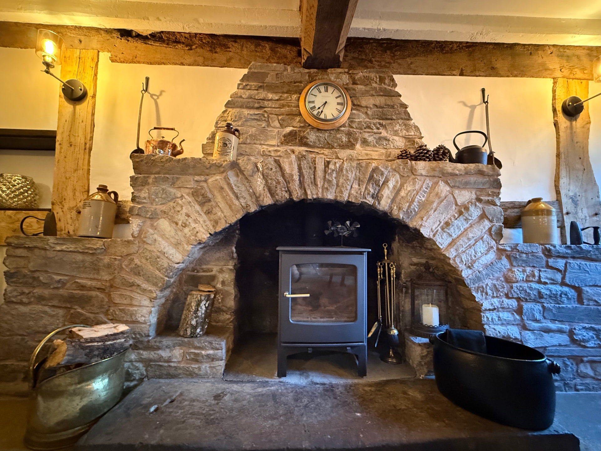 The stone inglenook fireplace with woodburner, copper kettles and antique clock